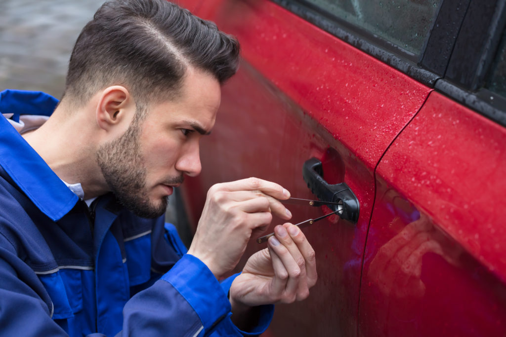 A locksmith unlocking a car door using a lockpicker