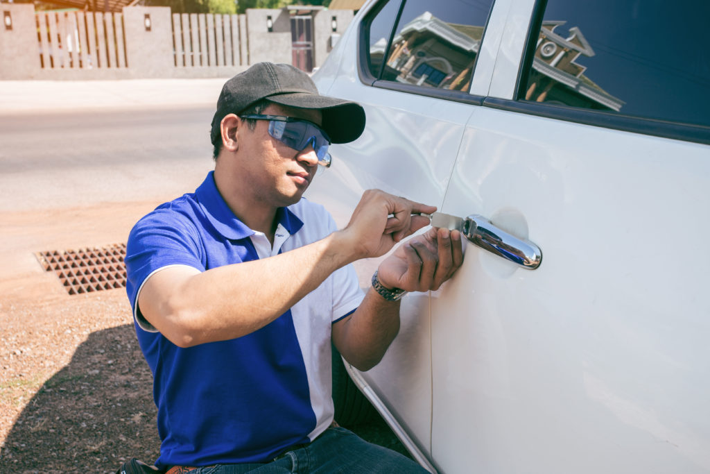 Locksmith unlocking a car door with a lockpicker