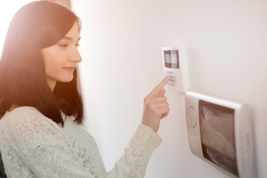 Woman entering code on home security keypad