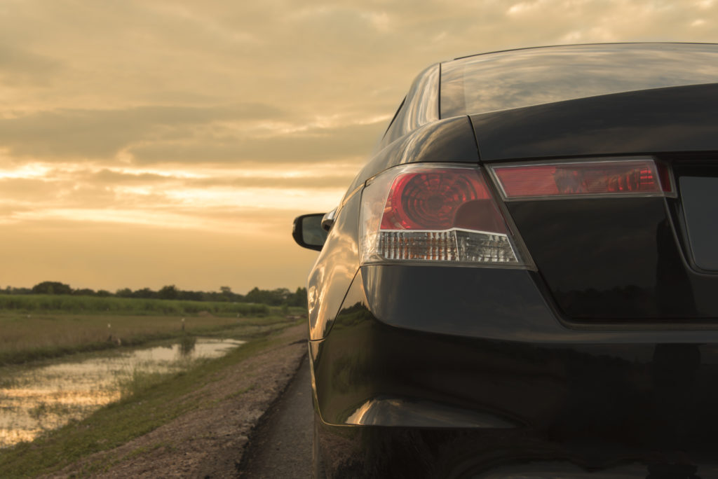 Trunk and taillight of a car in front of a setting sun