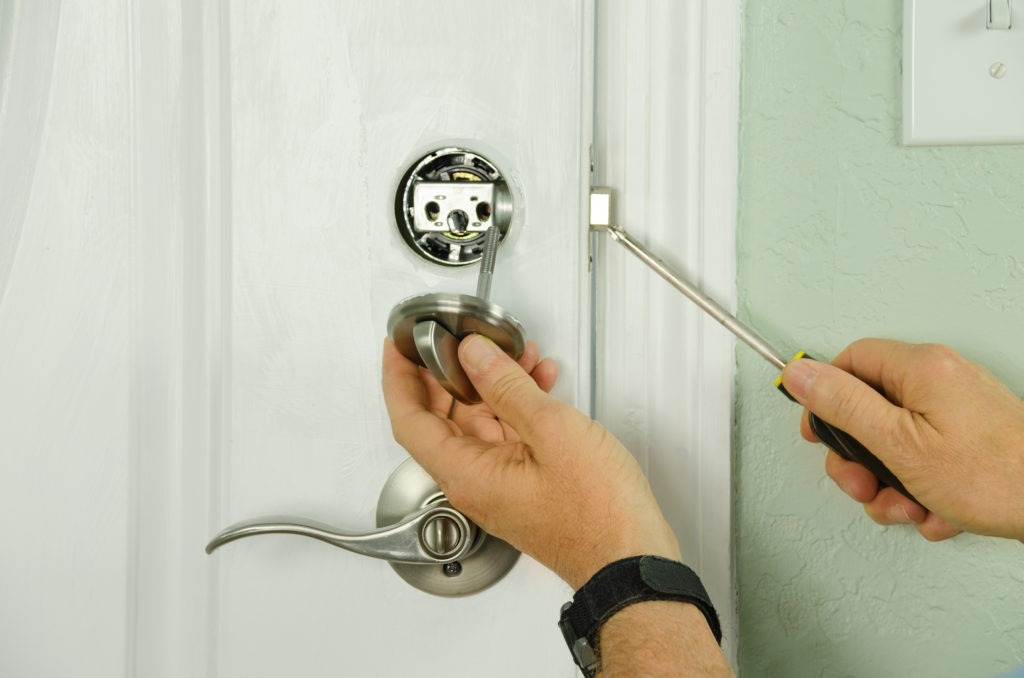 Locksmith replacing the deadbolt lock on a door