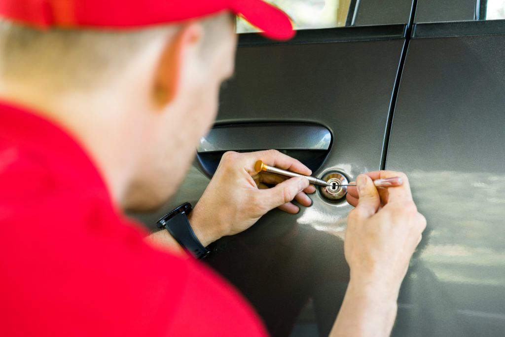 Locksmith opening car lock using specialized tools