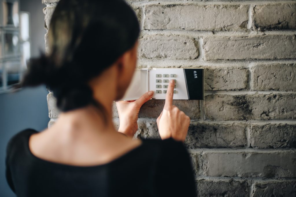 Woman entering pin on home security system