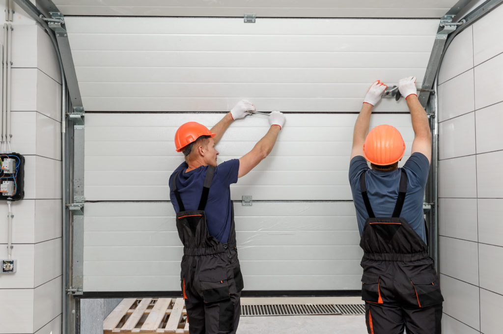 Two men repairing or replacing a garage door