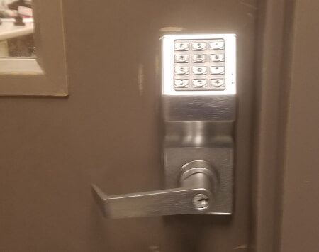 Commercial locksmith in Bryan, TX installing a keypad access control lock