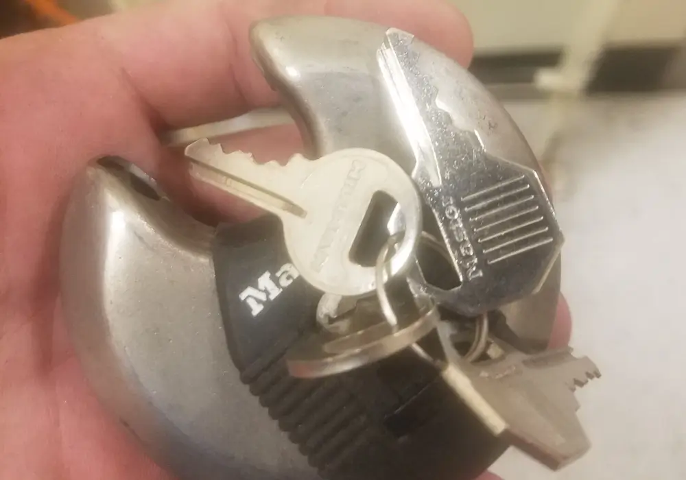 Round disc padlock with keys inserted held by locksmith in Houston TX