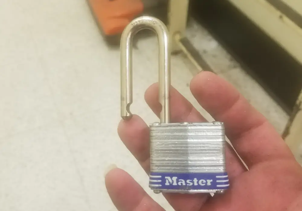Unlocked Master padlock with open shackle held by locksmith in Houston TX