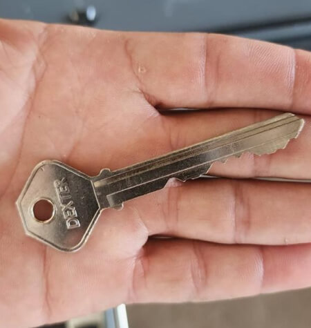 Worn car key held by a locksmith during ignition lock replacement in Dallas, TX